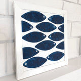 Angled view of Blue Fish wall art showing the white frame and hand-painted fish composition