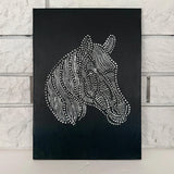 Horse relief canvas artwork displayed on a wall with a black background