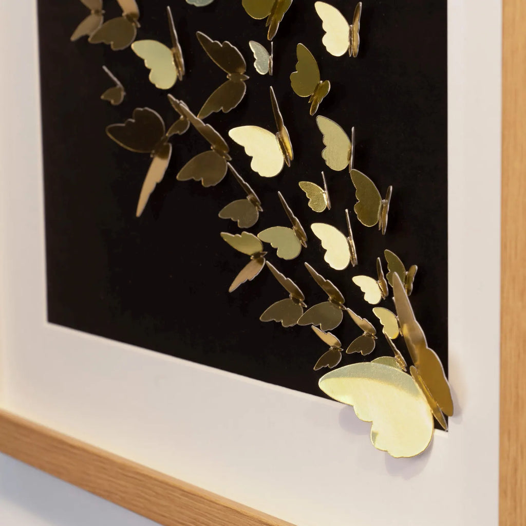 Side detail of handmade gold butterfly wall art extending beyond the frame