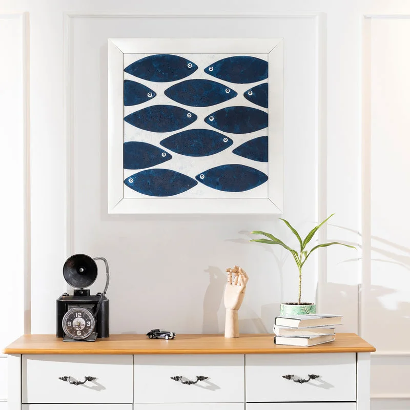 Angled view of indigo blue fish wall art showing the white frame and raised fish composition