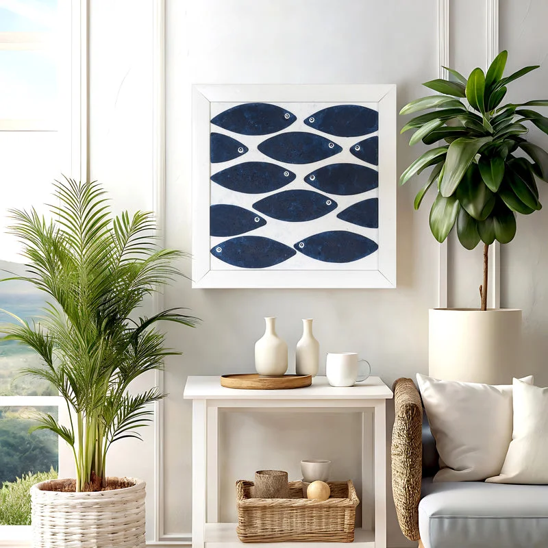 Indigo blue fish wall art in a white frame photographed from above with eucalyptus leaves around it