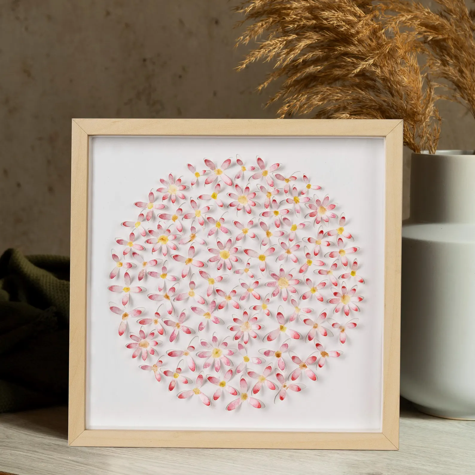 Angled view of pink daisy circle 3D watercolor wall art showing raised paper flower layers in a light wood frame